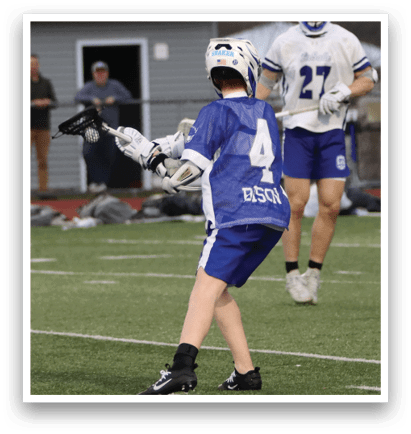 A young man in a blue jersey is holding a lacrosse stick, preparing to play. AI generated content