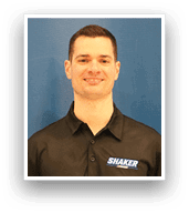 A man wearing a black shirt with the word shaker on it. Description generated by AI