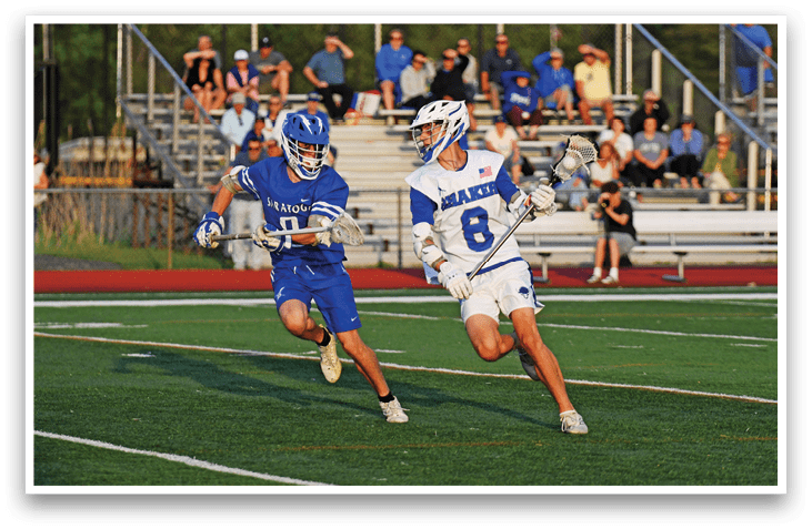 Two men playing lacrosse on a field. Description generated by AI