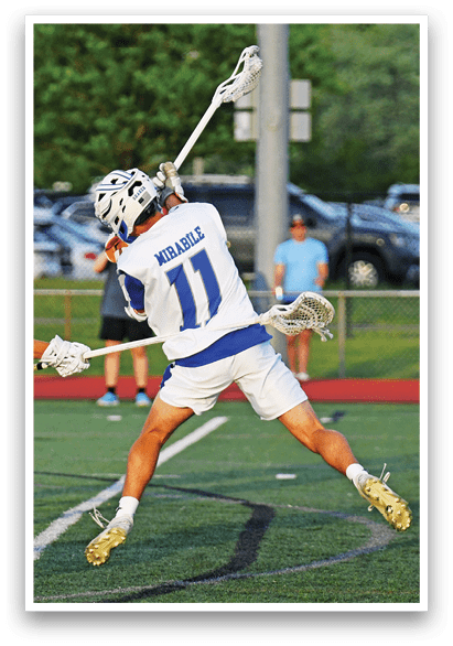 A man in a blue and white uniform is holding a lacrosse stick. Description generated by AI