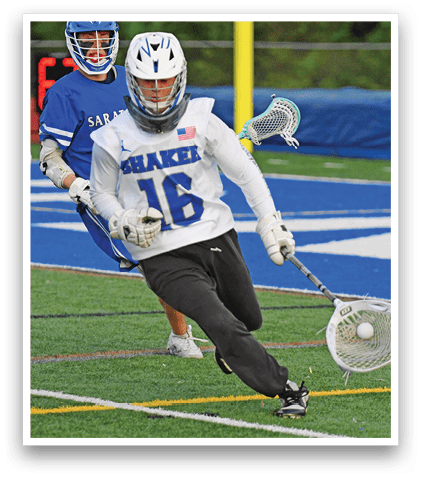 A man in a white and blue uniform is playing lacrosse. Description generated by AI