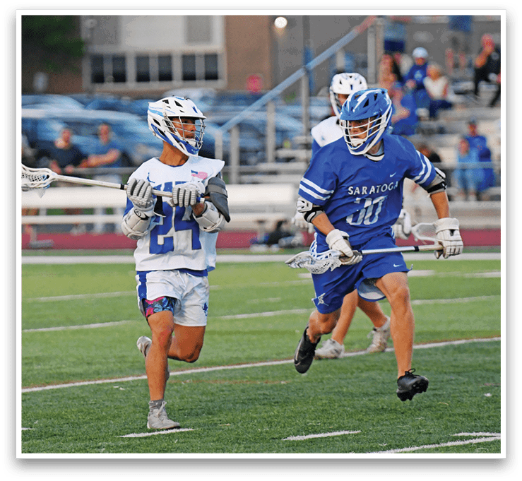 Two men playing lacrosse on a field. Description generated by AI