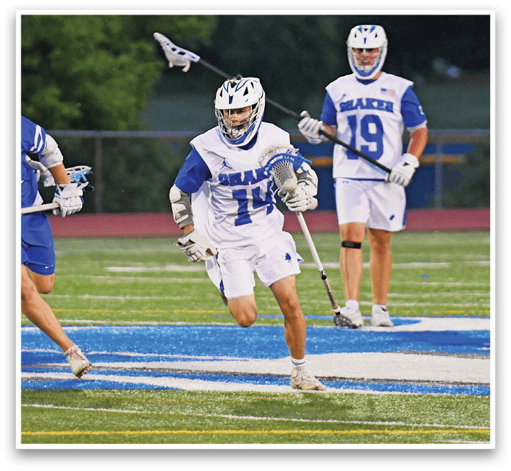 A man in a white jersey is holding a stick. Description generated by AI