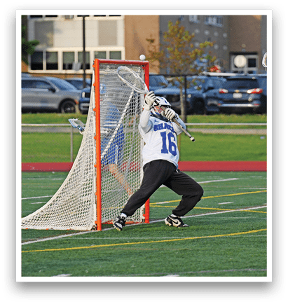 A man is trying to score a goal in a lacrosse game. Description generated by AI