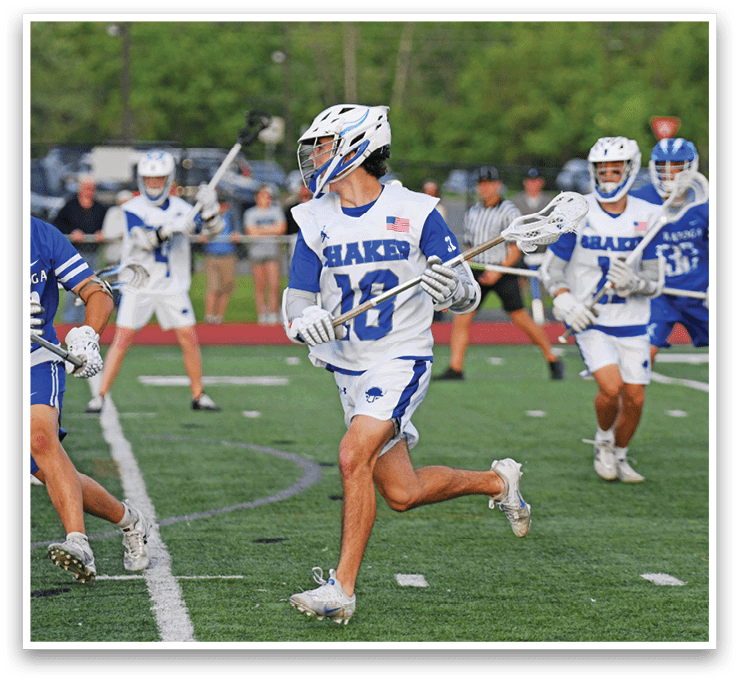 A group of young men playing lacrosse on a field. Description generated by AI