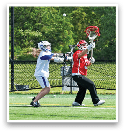 A man in a red shirt is holding a lacrosse stick. Description generated by AI
