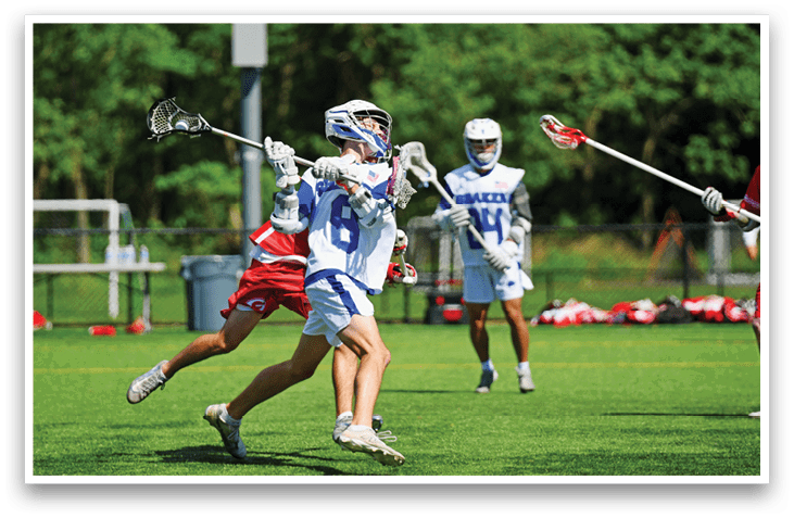 A man wearing a blue and white uniform is running with a lacrosse stick. Description generated by AI