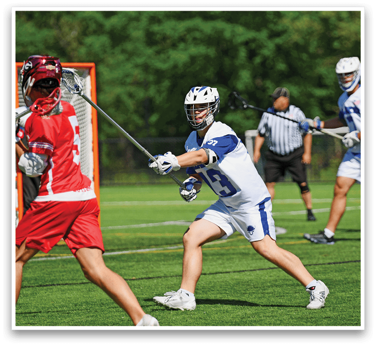 A man in a red shirt is holding a lacrosse stick. Description generated by AI