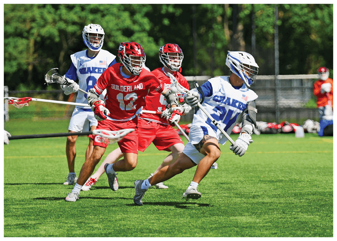 A group of men playing lacrosse on a field. Description generated by AI