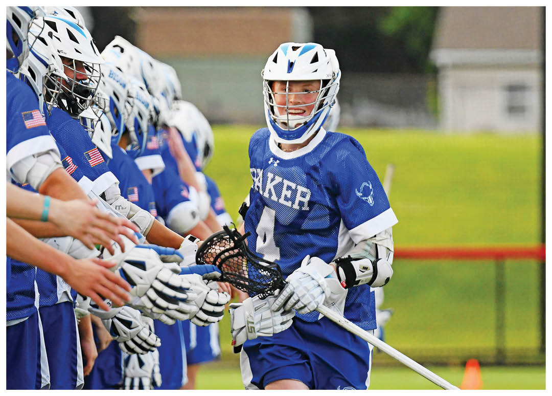 A group of men playing lacrosse on a field. Description generated by AI