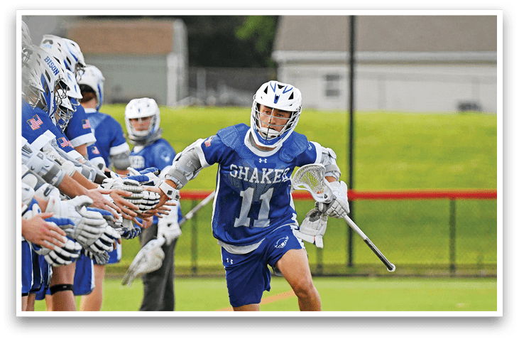 Two men playing lacrosse on a field. Description generated by AI