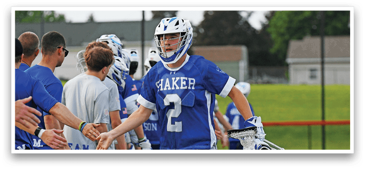 A man in a blue and white uniform is running with a lacrosse stick. Description generated by AI