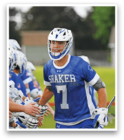 A man in a white and blue uniform is playing lacrosse. Description generated by AI