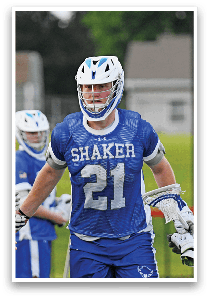 A man in a blue and white uniform is holding a lacrosse stick. Description generated by AI