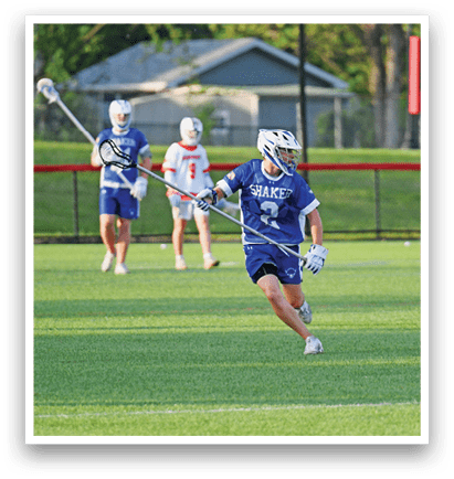 Three men playing lacrosse on a field. Description generated by AI