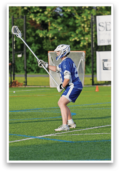 A man in a blue and white uniform is holding a lacrosse stick. Description generated by AI