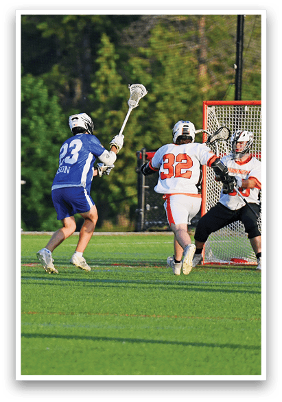 A man in a blue and white uniform is holding a lacrosse stick. Description generated by AI