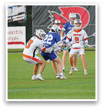 Three men playing lacrosse on a field. Description generated by AI