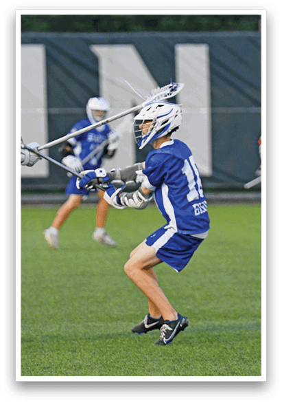 A man in a blue and white uniform is holding a lacrosse stick. Description generated by AI