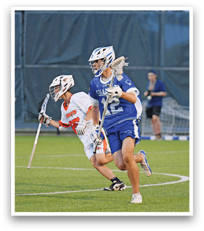 A man in a white and blue uniform is playing lacrosse. Description generated by AI