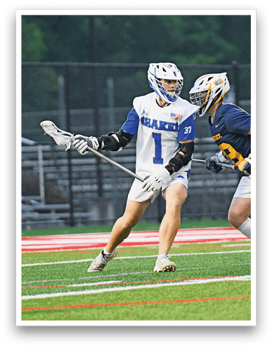 A person wearing a white and blue sports uniform and helmet is playing lacrosse on a field with red and white markings. Description generated by AI