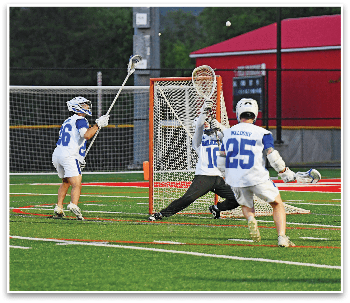 Three people in sports uniforms and helmets are playing lacrosse on a field with one person attempting to score a goal while another defends the net. Description generated by AI