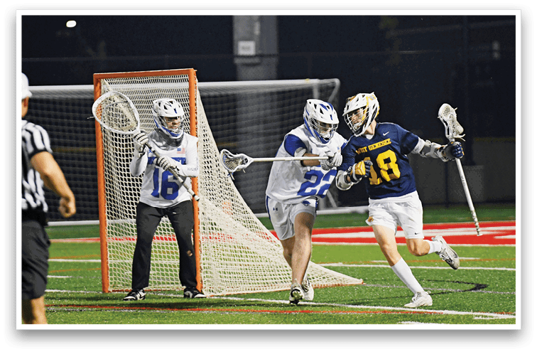 A person wearing a white and blue sports uniform is running near a lacrosse goal on a field at night. Description generated by AI