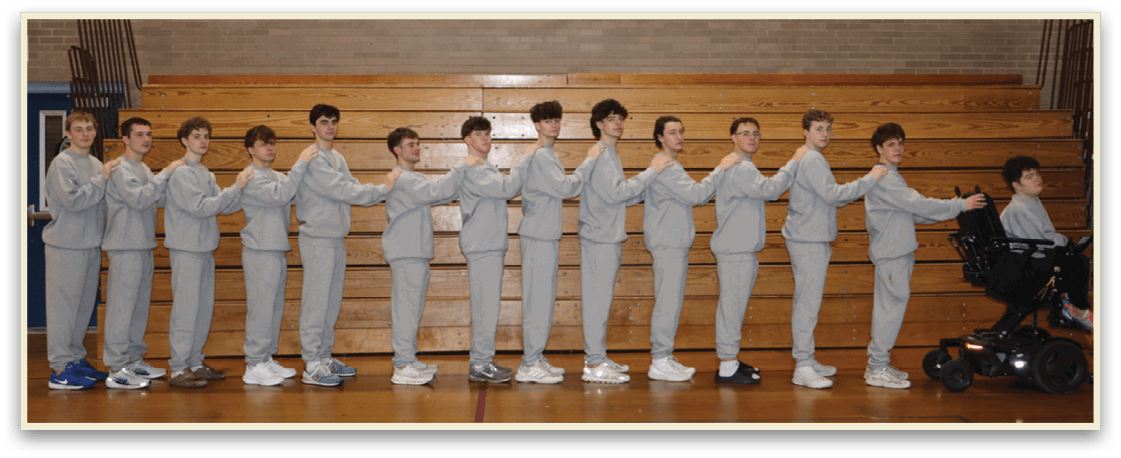 A group of young men are standing in a gym, wearing grey sweatshirts and white shoes. They are lined up in a row, with some of them holding hands with their neighbors. AI generated content
