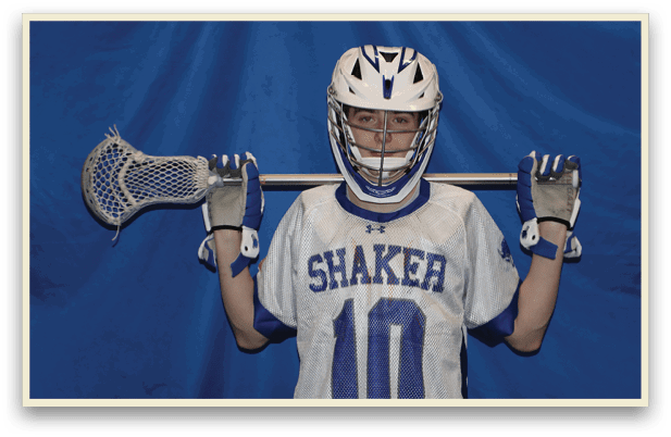A young man wearing a Shaker jersey holds a lacrosse stick. AI generated content