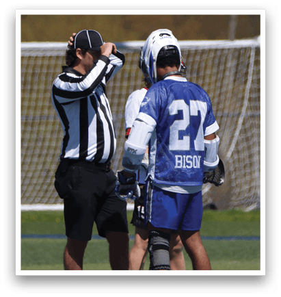 Three men are standing on a field, two of them wearing blue and white uniforms. One of the men in blue is wearing a helmet. The referee is standing between the two players, possibly discussing a play. AI generated content