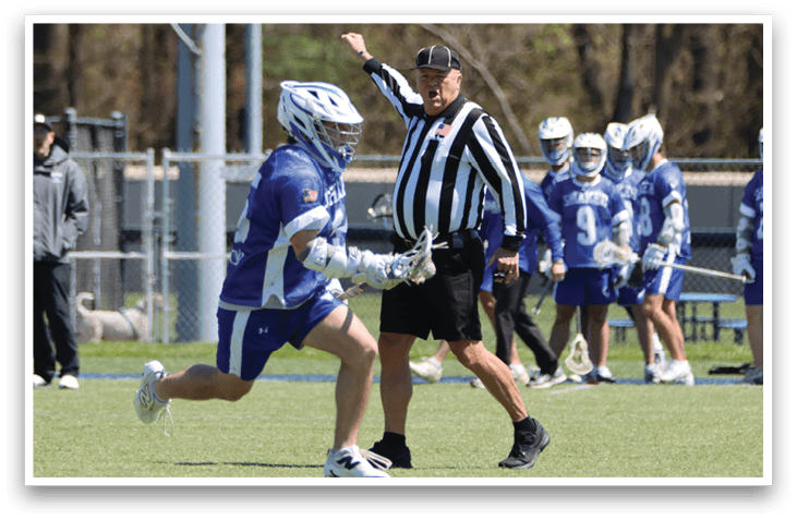 A group of people playing a game of lacrosse. A man in a blue uniform is running with a lacrosse stick. A referee is standing behind him, wearing a black and white striped shirt. AI generated content