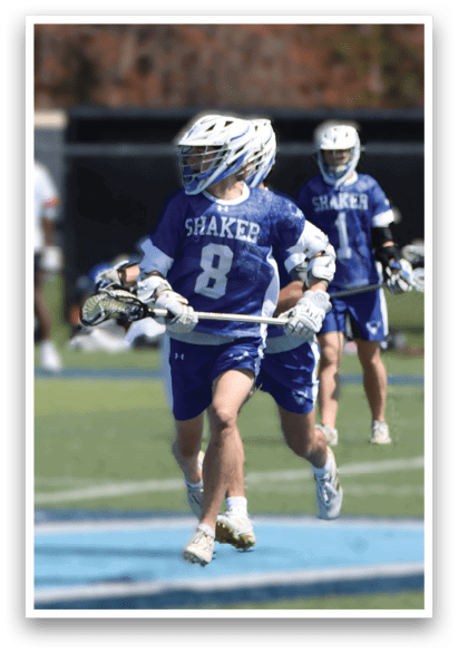 A lacrosse game is in progress with players running across the field. The players are wearing uniforms and helmets, and one player is holding a lacrosse stick. The game is being played on a field with a blue and white color scheme. AI generated content