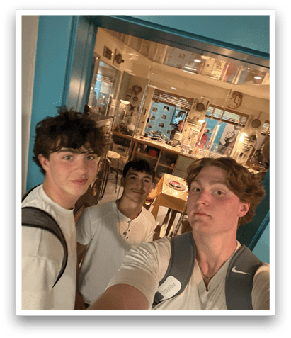 Three young men are standing in a room, posing for a picture. They are wearing white shirts and one of them is holding a cell phone. AI generated content