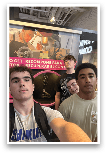 Four young men pose for a picture in front of a pink sign. AI generated content