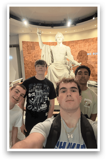 Four young men pose in front of a statue of a man. AI generated content
