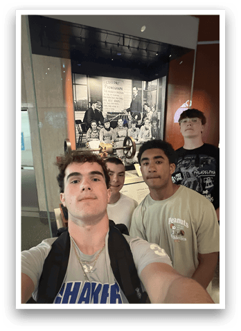 Four young men pose for a picture in front of a museum display. AI generated content