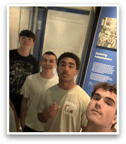 Four young men pose for a picture in front of a display. AI generated content
