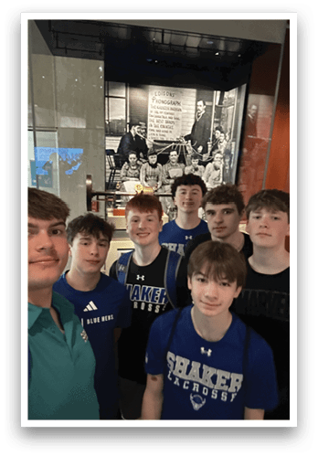 A group of young men in blue shirts pose for a picture in front of a framed photo. AI generated content