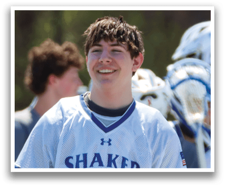 A young man wearing a white jersey with the word Shaker on it is holding a lacrosse stick. AI generated content