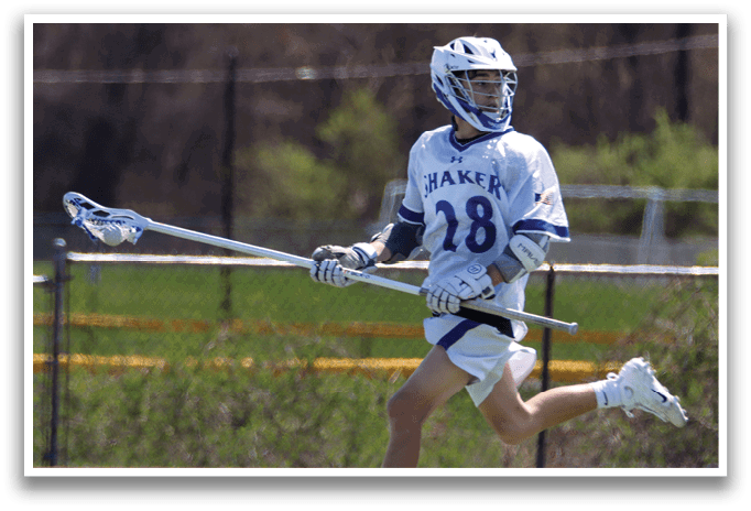 A man wearing a white and blue uniform is running on a field while holding a lacrosse stick. AI generated content