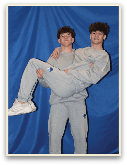 Two young men are posing for a picture, one of them is holding the other's legs. AI generated content