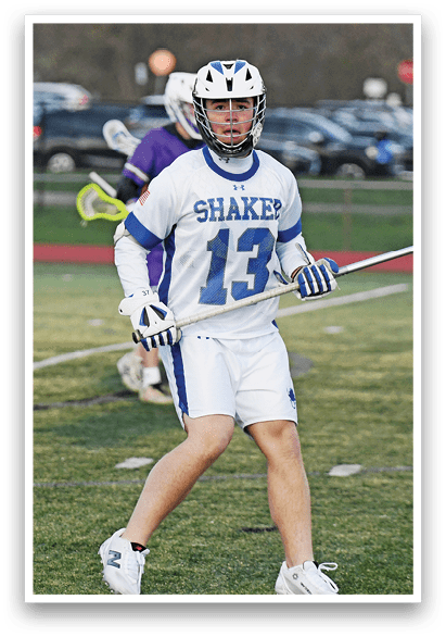 A man in a white and blue uniform is holding a lacrosse stick while standing on a field. AI generated content
