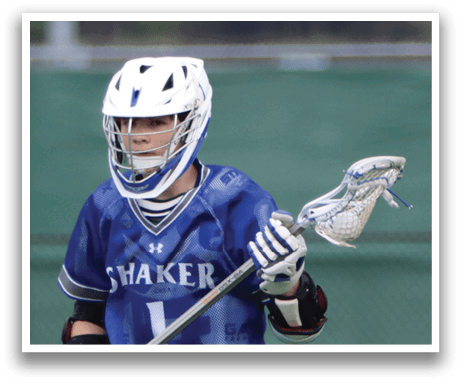 A young man wearing a blue and white jersey stands on a field holding a lacrosse stick. AI generated content