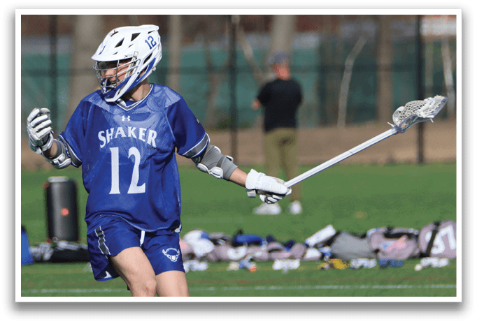 A man wearing a blue and white jersey with the number 12 on it is holding a lacrosse stick and walking across a field. AI generated content