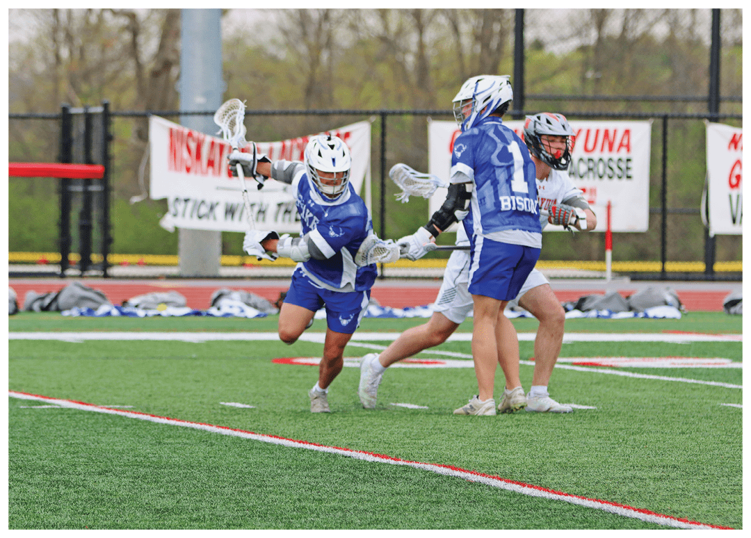A group of people playing lacrosse on a field. Description generated by AI