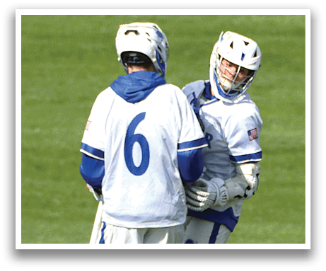 Two men wearing white and blue uniforms are standing on a grassy field. Description generated by AI