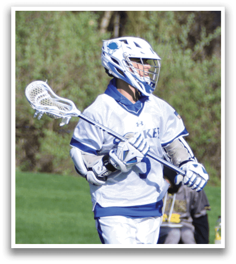 A man wearing a white and blue jersey is holding a lacrosse stick. Description generated by AI