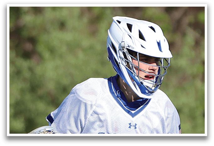 A man wearing a white and blue shirt and black pants holding a lacrosse stick. Description generated by AI