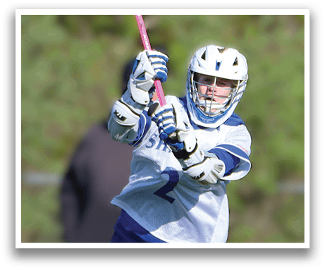 A man holding a pink and white lacrosse stick. Description generated by AI