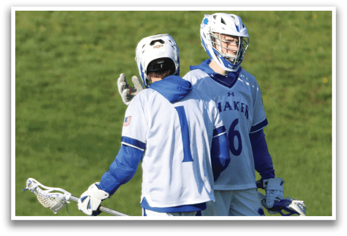 Two lacrosse players wearing blue and white uniforms. Description generated by AI